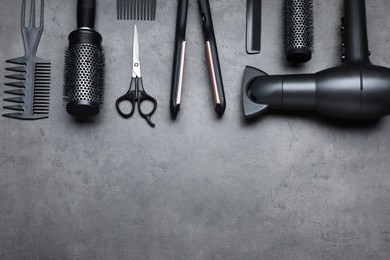 Flat lay composition of professional hairdresser tools on dark grey table, space for text