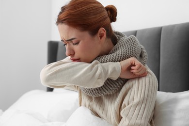 Photo of Woman with scarf coughing at home. Cold symptoms