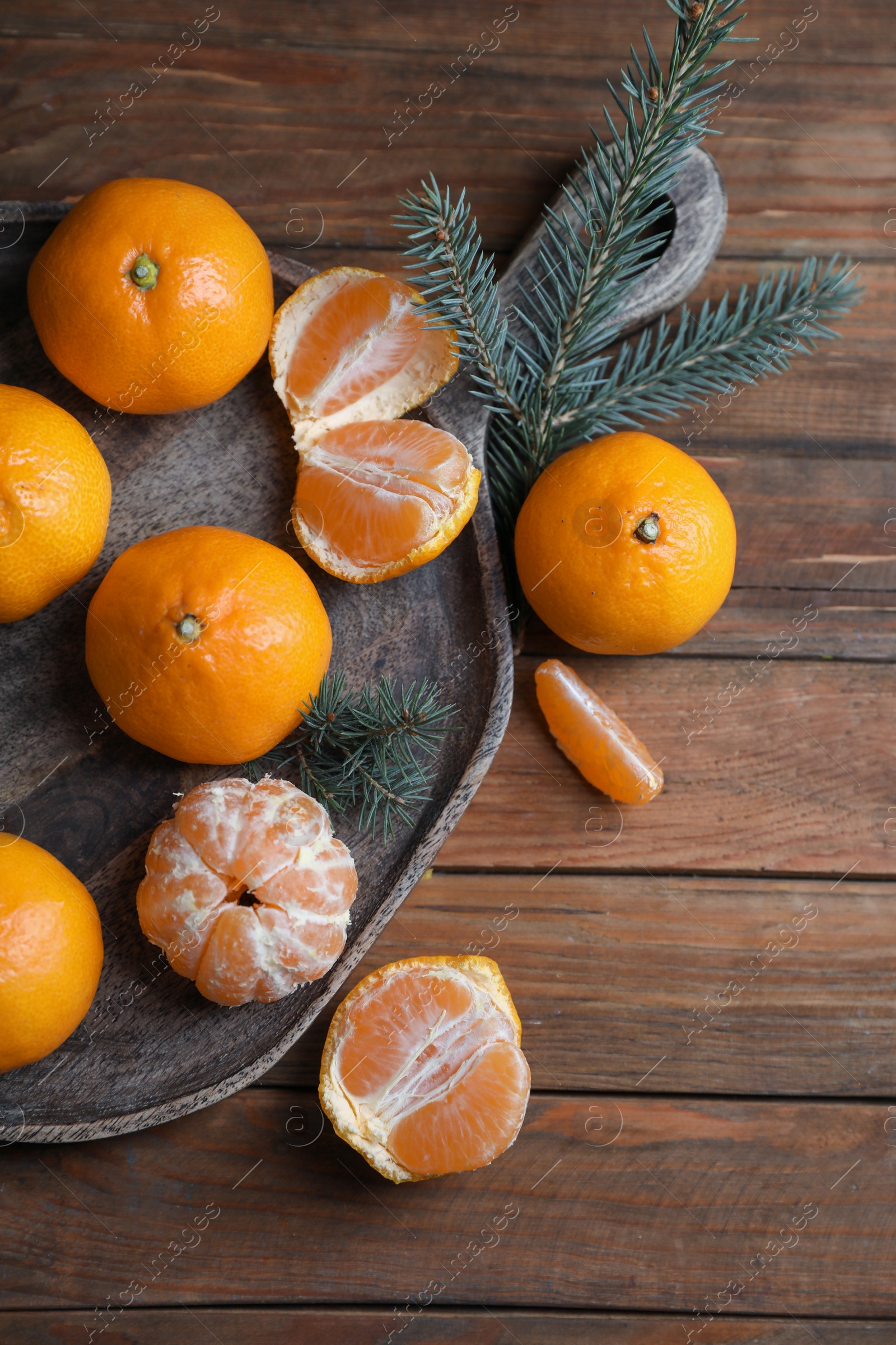 Photo of Tray with delicious ripe tangerines and fir branches on wooden table, flat lay