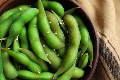 Photo of Bowl with green edamame beans in pods on table, top view