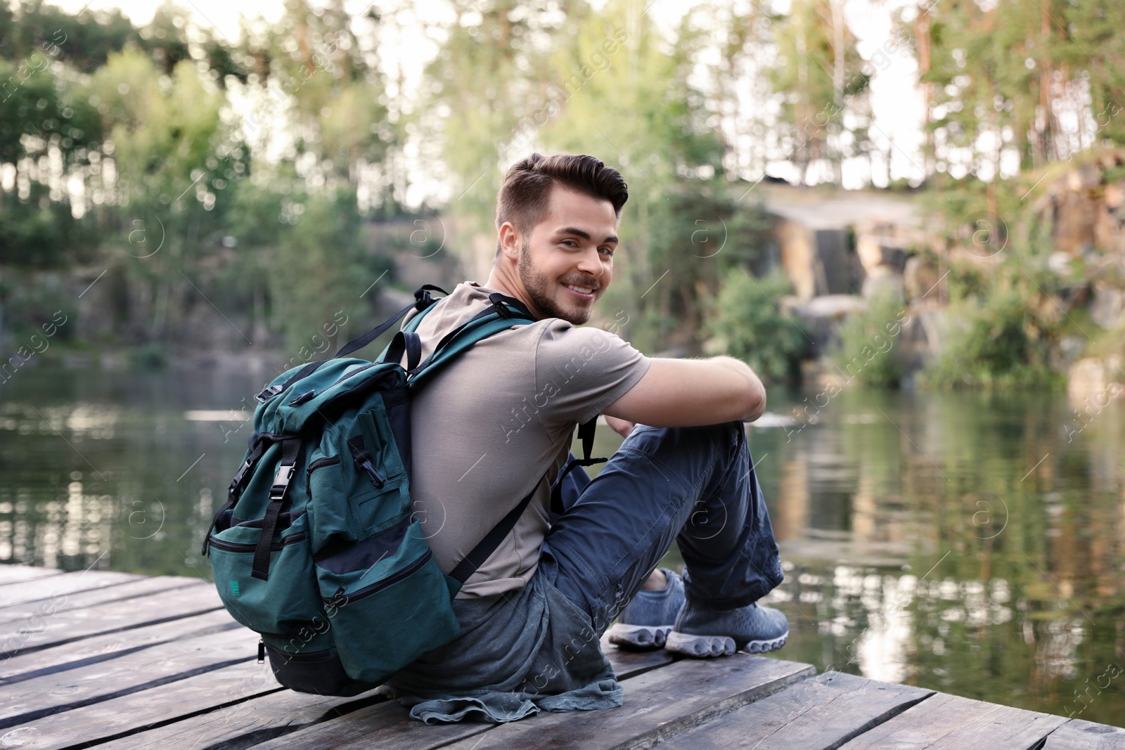 Photo of Young man on wooden pier near lake. Camping season