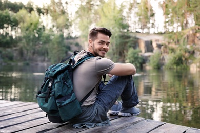 Photo of Young man on wooden pier near lake. Camping season