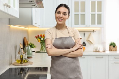Photo of Young woman wearing apron near cooktop in kitchen