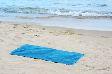 Photo of Blue towel on sandy beach near sea, space for text