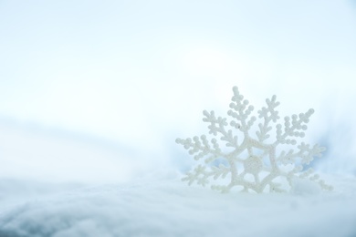 Photo of Beautiful decorative snowflake in white snow, outdoors. Space for text