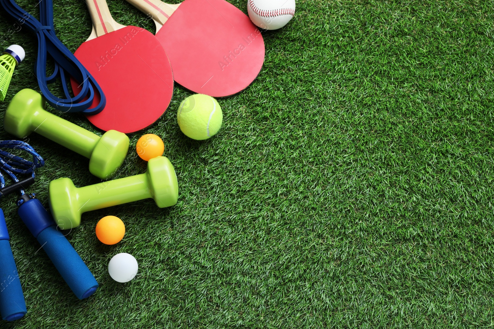 Photo of Set of different colorful sports equipment on green grass, flat lay. Space for text