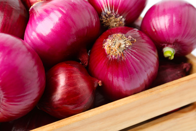Many fresh red onions in wooden crate, closeup