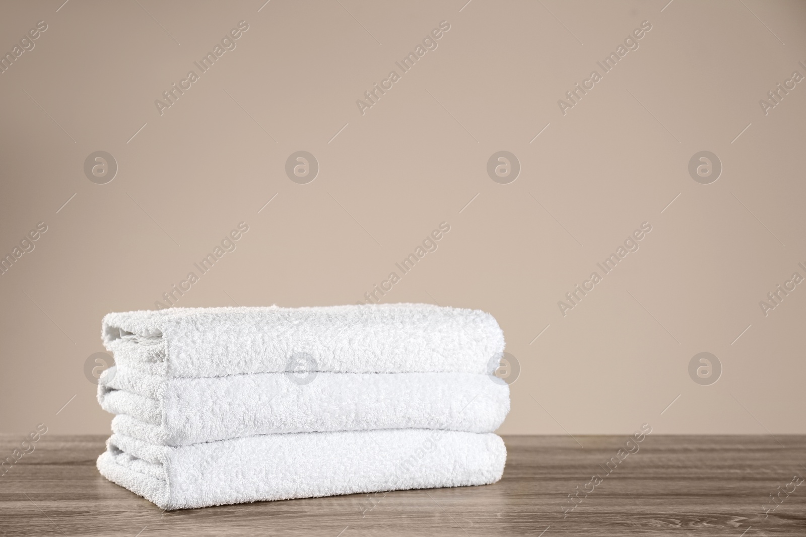 Photo of Stack of clean bath towels on wooden table. Space for text