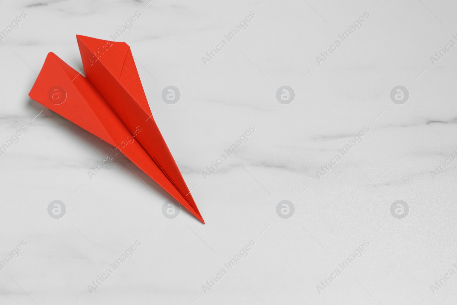 Photo of Handmade paper plane on white marble table, top view. Space for text