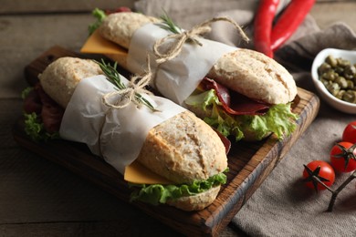 Delicious sandwiches with bresaola, cheese and lettuce on wooden table, closeup