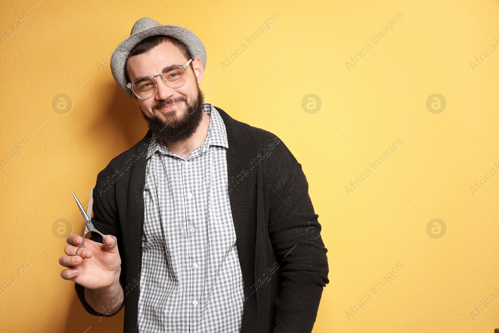 Photo of Professional hairdresser with scissors on color background