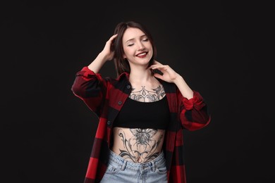 Photo of Portrait of smiling tattooed woman on black background