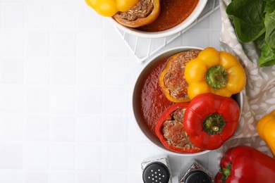 Photo of Delicious stuffed bell peppers on white tiled table, flat lay. Space for text