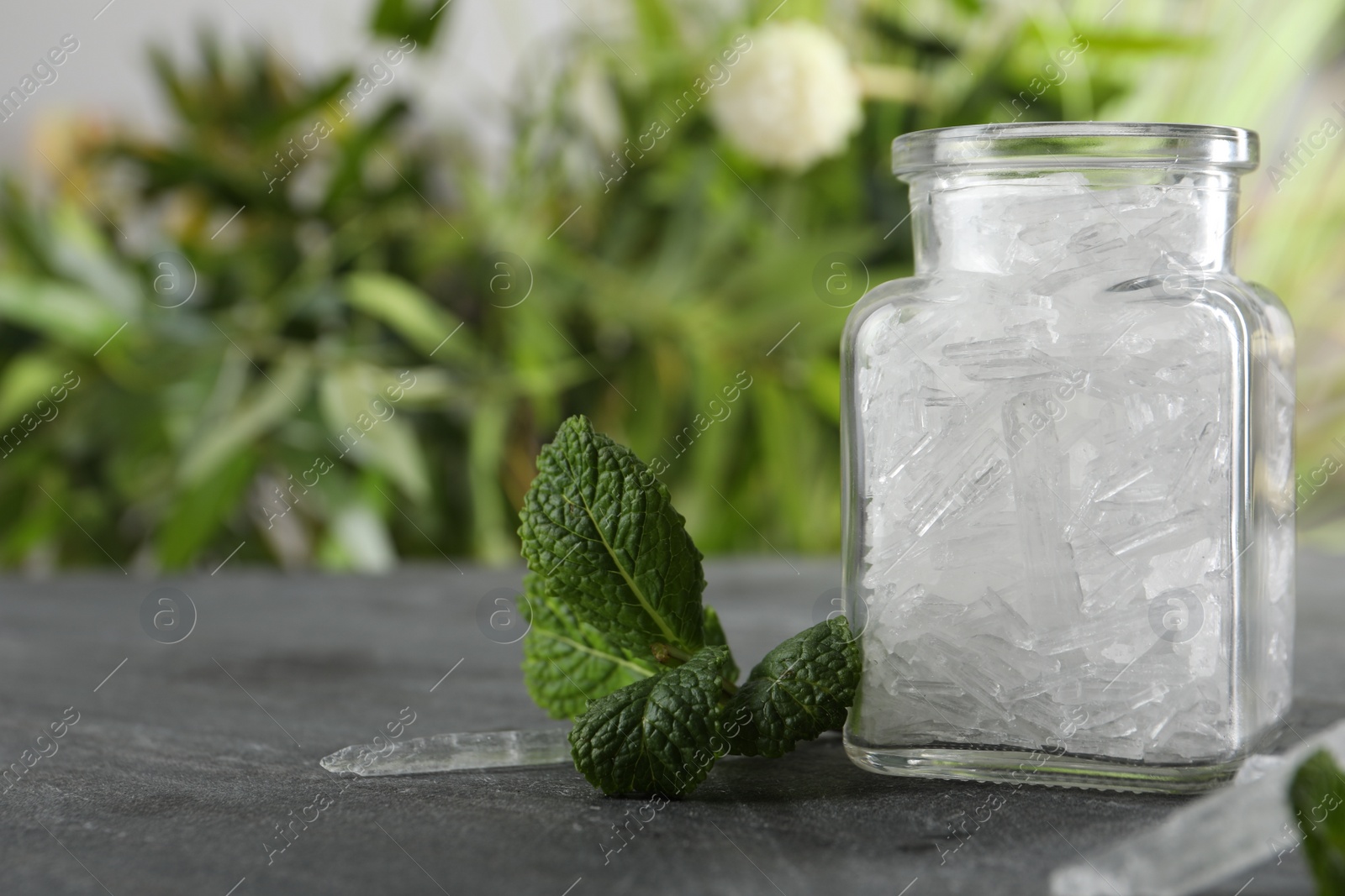 Photo of Menthol crystals and mint leaves on grey background. Space for text