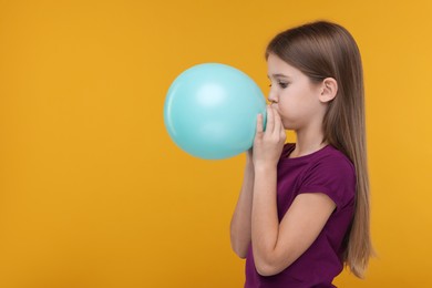 Girl inflating bright balloon on orange background, space for text