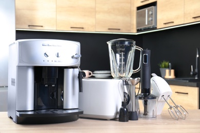 Photo of Modern domestic appliances on wooden table in kitchen