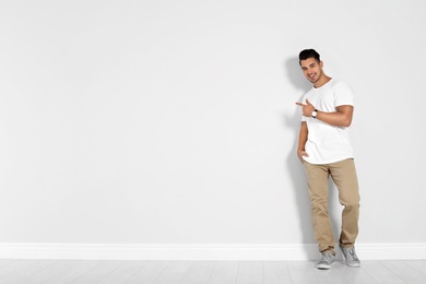 Photo of Full length portrait of handsome young man and space for text on white wall background