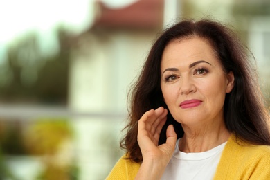 Portrait of beautiful older woman against blurred background with space for text