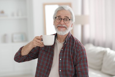 Photo of Portrait of happy grandpa with glasses and cup of drink indoors