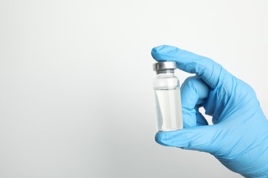 Photo of Doctor holding vial with medication on white background, closeup view and space for text. Vaccination and immunization
