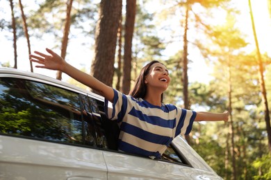 Enjoying trip. Happy young woman leaning out of car window, low angle view