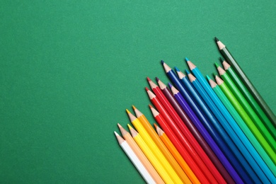 Photo of Color pencils on green background, flat lay. Space for text