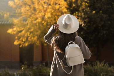 Young woman with stylish white backpack on city street, back view. Space for text