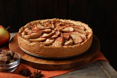 Photo of Delicious apple pie and ingredients on wooden table