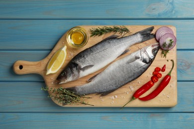 Photo of Sea bass fish and ingredients on light blue wooden table, top view