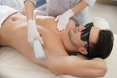 Young man undergoing laser epilation procedure in beauty salon