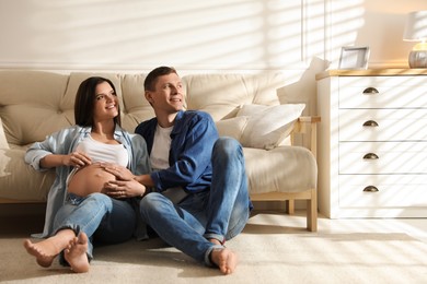 Photo of Young pregnant woman with her husband at home