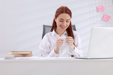 Woman popping bubble wrap at desk in office. Stress relief