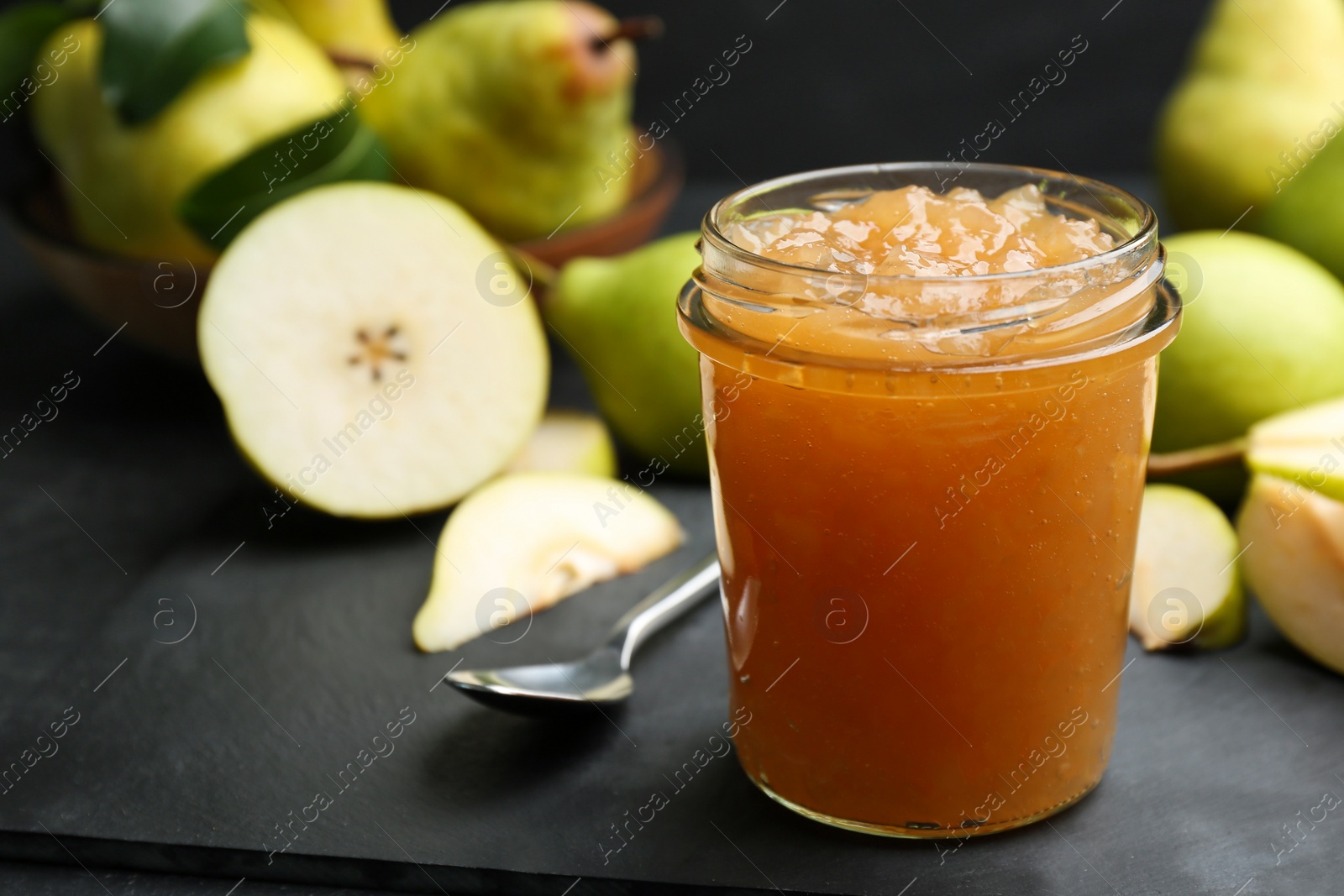 Photo of Tasty homemade pear jam and fresh fruits on black table