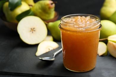 Tasty homemade pear jam and fresh fruits on black table