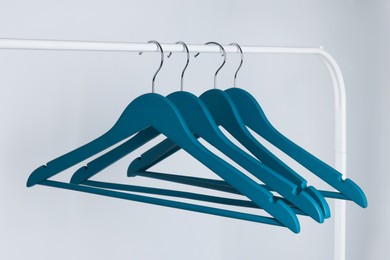Photo of Blue clothes hangers on metal rack against light background