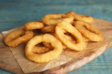 Photo of Fried onion rings served on blue wooden table, closeup