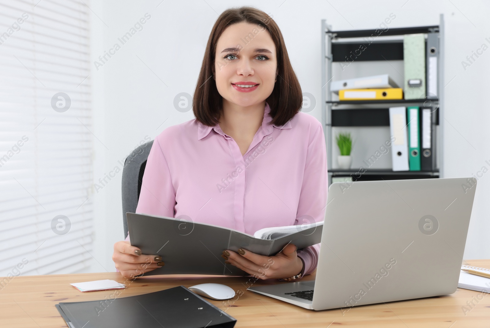 Photo of Happy young intern working at table in modern office