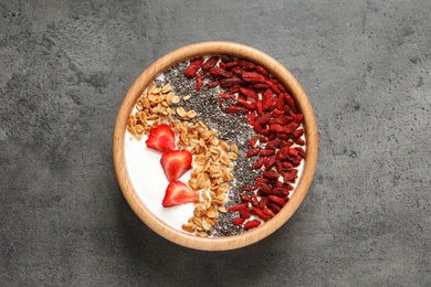 Smoothie bowl with goji berries on grey table, top view