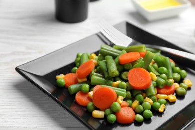 Plate with tasty vegetable salad on white wooden table, closeup