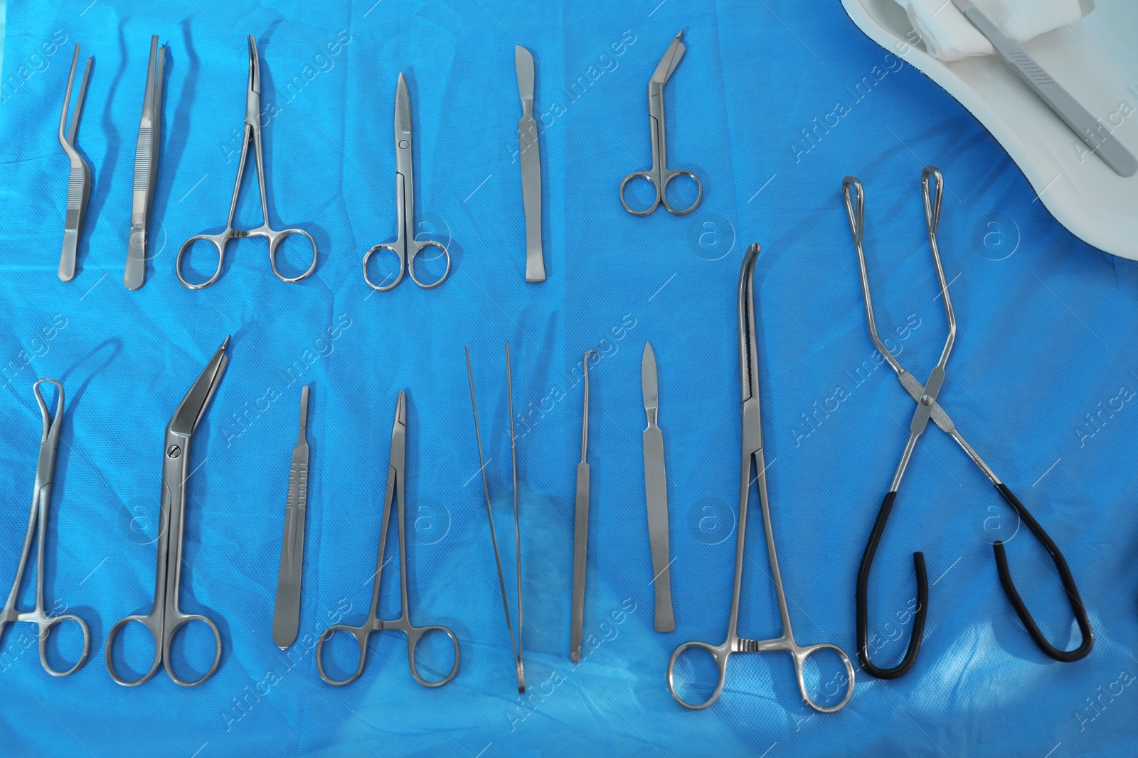 Photo of Different surgical instruments on blue table, flat lay