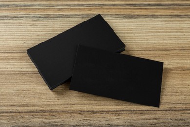 Blank black business cards on wooden background, above view. Mockup for design