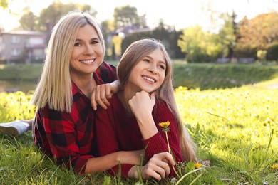 Happy mother with her daughter on green grass in park