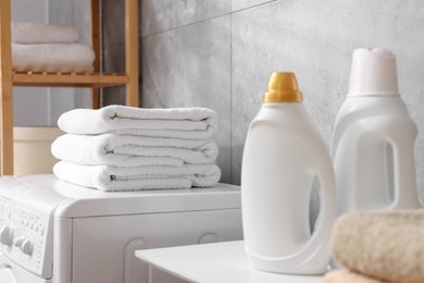 Photo of Soft towels, detergents and washing machine indoors, closeup