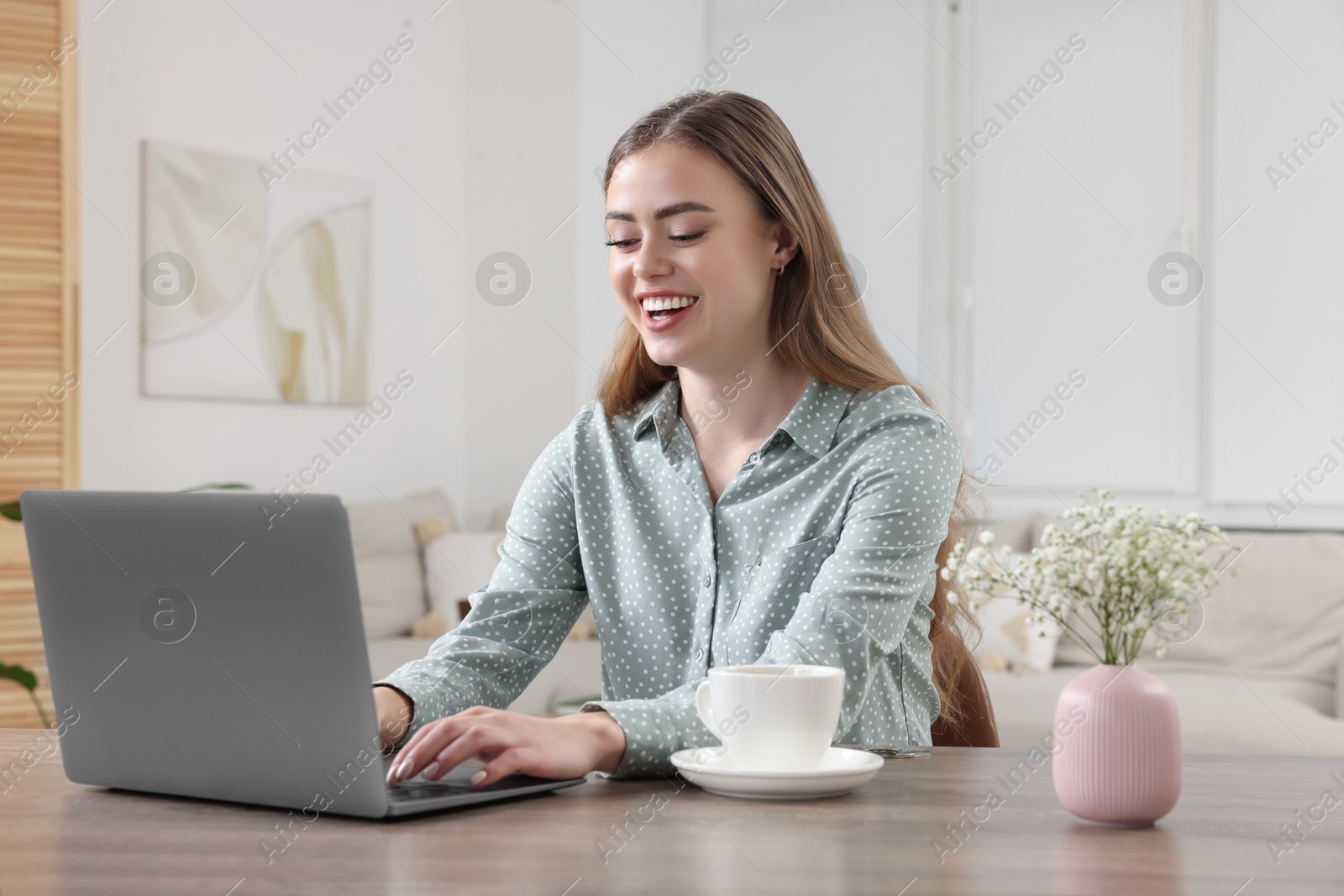 Photo of Happy woman with laptop at wooden table in room