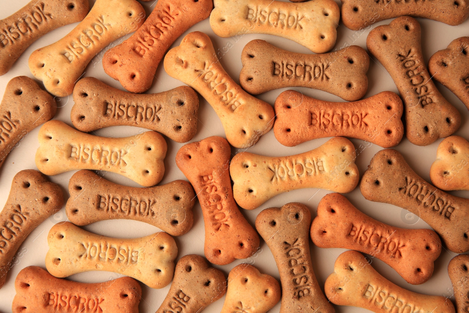 Photo of Bone shaped dog cookies on beige background, flat lay