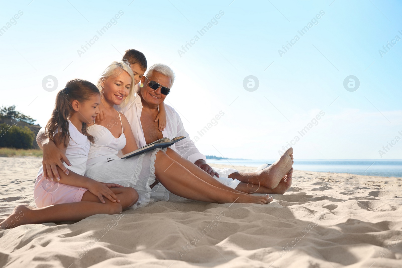 Photo of Cute little children with grandparents spending time together on sea beach