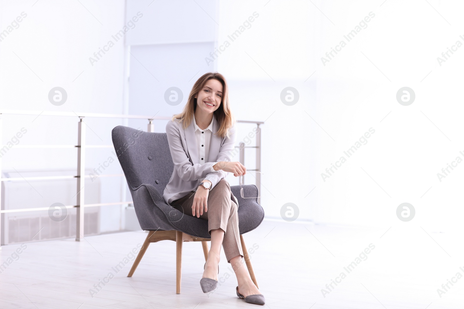 Photo of Beautiful young businesswoman sitting in armchair indoors. Space for text
