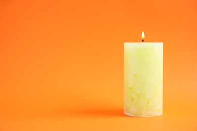 Alight wax candle on color background. Space for text