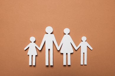 Photo of Paper family figures on brown background, top view. Insurance concept