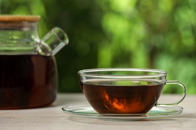 Cup of aromatic tea on white table outdoors, closeup